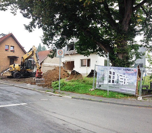 Bagger arbeitet an einem Hausabriss auf Baustelle.