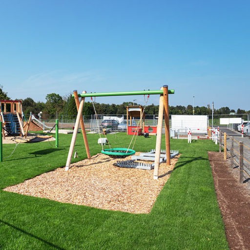 Moderner Spielplatz mit Schaukel und Rutsche.