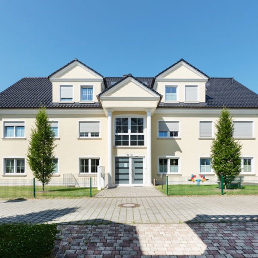 Modernes Mehrfamilienhaus mit Garten und blauer Himmel.