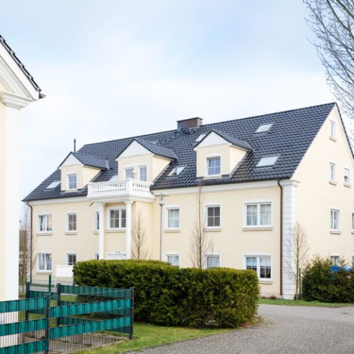 Gelbes Wohnhaus mit schwarzem Dach und Balkon