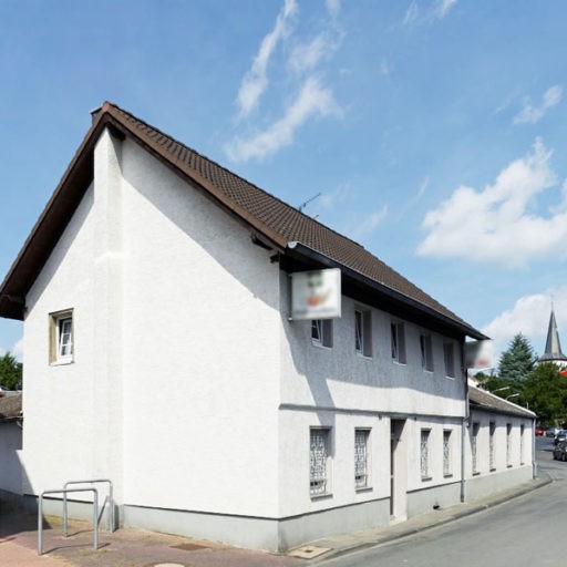 Eckhaus in einer Wohnstraße mit Kirche im Hintergrund.