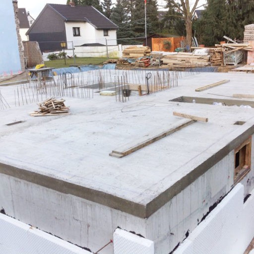 Baustelle mit Betonfundament und Baumaterialien