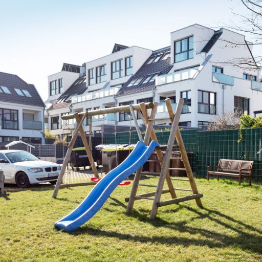 Spielplatz mit Rutsche vor Wohnungen im Freien.