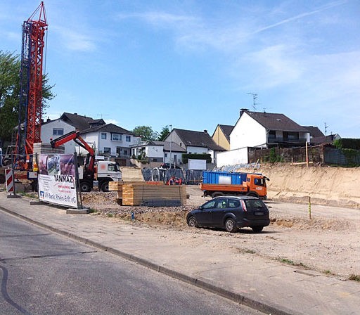 Baustelle mit Baukran und Fahrzeugen in Wohngebiet